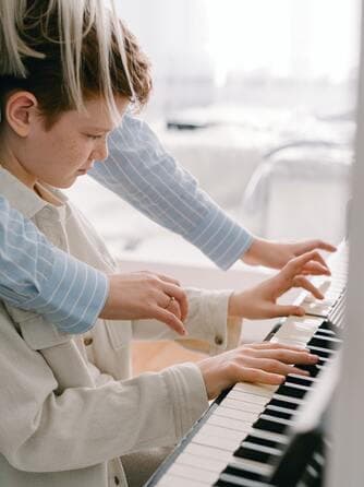 Une professeure guide les mains d’un jeune pianiste